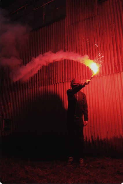  Delwedd o ddyn yn dal dyfais pyro coch i fyny